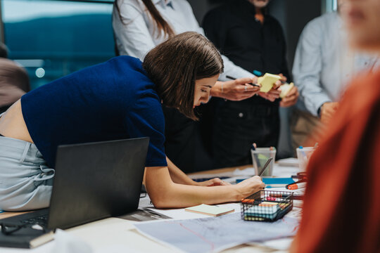 Multigenerational and multicultural business team engaged in brainstorming session to meet a deadline. Colleagues working late into the evening, analyzing project solutions and discussing ideas.