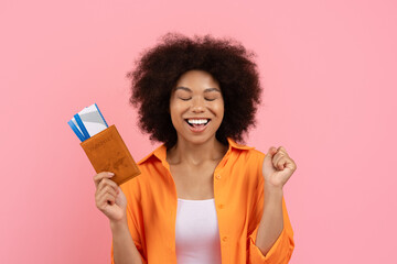Delighted young black woman with closed eyes holding passport and tickets. Peaceful and joyful...