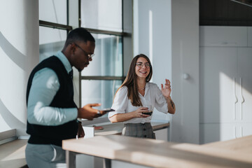 Multicultural business workers smiling and enjoying a relaxing break in a modern office environment, fostering camaraderie and teamwork. Natural light enhances the friendly and casual atmosphere.