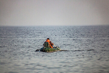 A fisherman rows in an inflatable boat in the sea