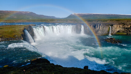 Majestic Godafoss waterfall in Iceland with a vibrant rainbow arching over the cascading waters
