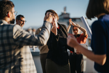 A group of multicultural business people joyfully celebrating on a high tower balcony during sunset, showcasing diversity and teamwork. The image captures a moment of camaraderie and bright, happy