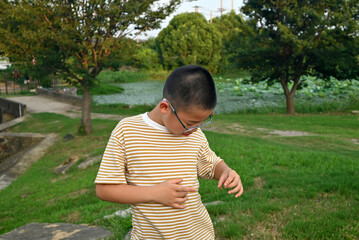 an asian boy with glasses on the grassland in sunny afternoon