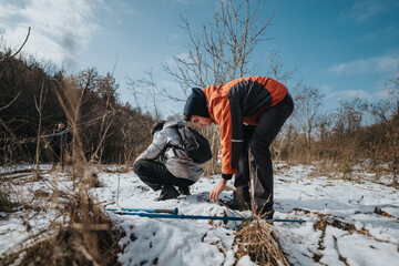 Young people engage in outdoor exploration during a winter day, observing nature and the...