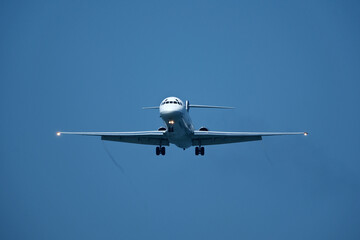 The plane approaching the airport. The plane is preparing to land. Airplane in the blue sky.