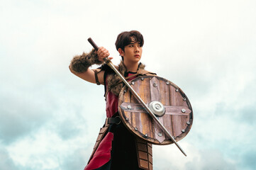 Portrait young handsome Viking worrier man holding sword and shield 