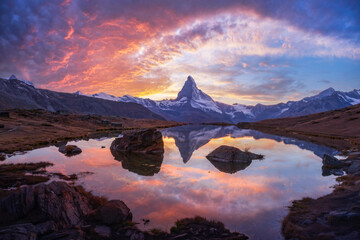 Dramatic light paints Stellisee and Matterhorn in vibrant colors during Swiss sunset. Iconic...