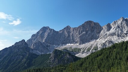 Towering Limestone Peaks and Verdant Forests of the Austrian Alps on a Clear Summer Day