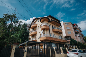 A contemporary apartment building featuring creatively designed balconies, surrounded by trees,...