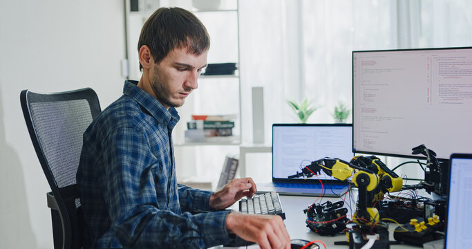 Young adult male freelance developer typing write prompt AI bot app program nomad terminal with coding at office. Artificial intelligence dashboard, robotics, user interface, machine learning concept.