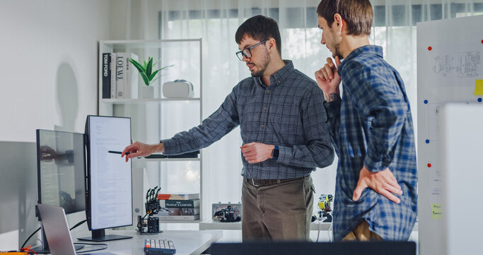 Team adult male engineer collaborate on robotic hand project using AI code solutions machine learning at tech workspace. Artificial intelligence interface, collaboration support prototype development.