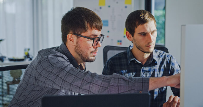 Team adult male engineer collaborate on robotic hand project using AI code solutions machine learning at tech workspace. Artificial intelligence interface, collaboration support prototype development.