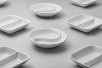 A collection of white ceramic dishes arranged on a gray surface.