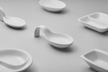 A collection of minimalist white ceramic tableware is arranged on a gray surface