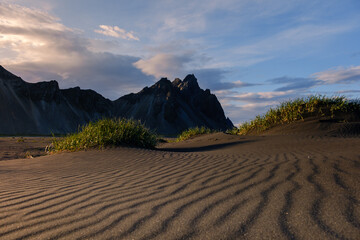 Majestic landscape of Iceland with towering mountains and textured sandy dunes under a dramatic sky