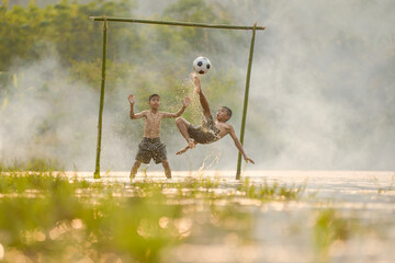 Asian children playing football at the river.