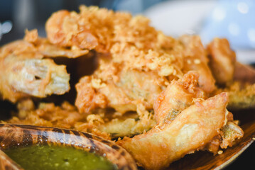 Close-up of fried food. Crispy fried fish or seafood pieces coated in batter and deep-fried until golden brown and crispy. Food arranged on a dark wooden plate.