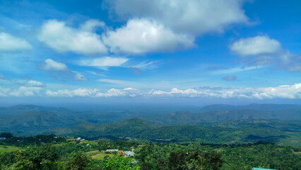 A cloudy blue sky over a green mountain region