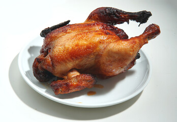 Roasted crispy brown whole chicken isolated on white plate and white background  