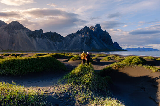 Couple exploring the stunning black sand dunes near Vestrahorn in Iceland at sunset