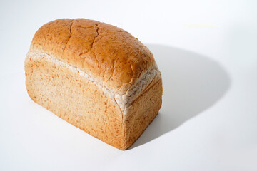 Fresh baked golden brown multigrain bread loaf on a white background.    