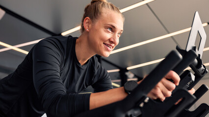 Young woman exercising on a stationary bike in a modern gym setting