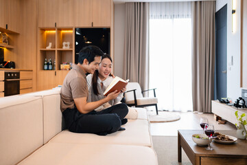 Couple reading books while resting on sofa together at home