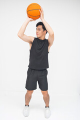A proud young Asian man poised to take a basketball shot, exuding confidence and focus. Isolated on...