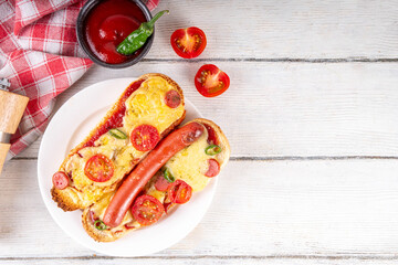 Tasty gourmet pizza dogs trendy viral combination recipe of hot dogs with hot sausage and pizza with tomatoes, cheese, jalapeno peppers, cherry tomatoes and herbs, with sauce on white wooden table