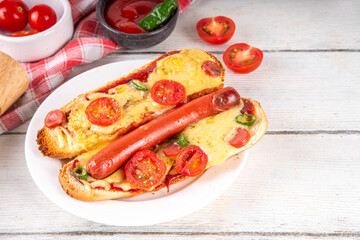 Tasty gourmet pizza dogs trendy viral combination recipe of hot dogs with hot sausage and pizza with tomatoes, cheese, jalapeno peppers, cherry tomatoes and herbs, with sauce on white wooden table
