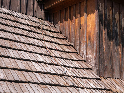 Detail of a wooden shingle roof and wall with lightning rod on a historic church in Bodruzal, Slovakia. Traditional architecture with natural wood texture.