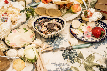 Messy Tea Party Assorted cookies candies and sweets served on decorative plates at table