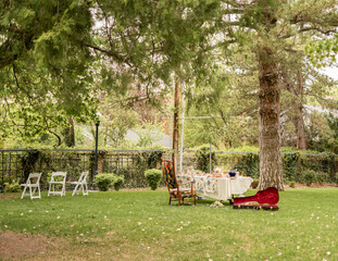garden scene with a decorated tea party table, empty chairs, a colorful armchair, and an open guitar