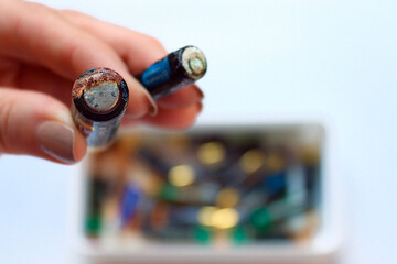 Hand holding corroded batteries with visible leakage