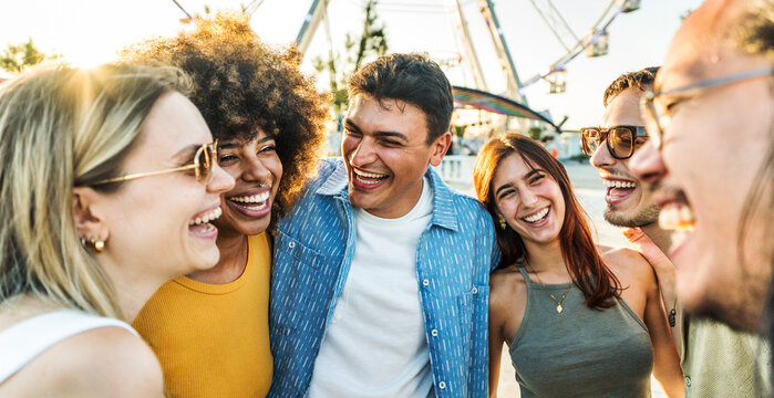 Multiethnic young people laughing together outside - Friendship life style concept with guys and girls having fun together hanging outdoors - Boys and girls talking and smiling on city street