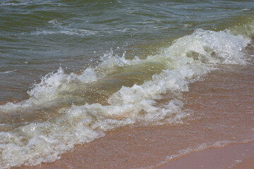 Soft wave of the sea on the sandy beach. Small waves on a sandy beach. The concept of summer, relaxation, and swimming