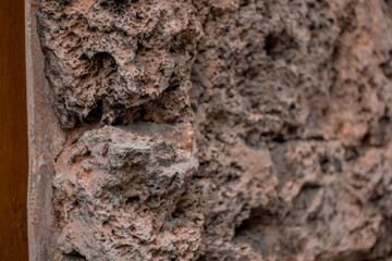 Detailed view of a porous, rugged volcanic rock wall with natural earthy tones, commonly used in...