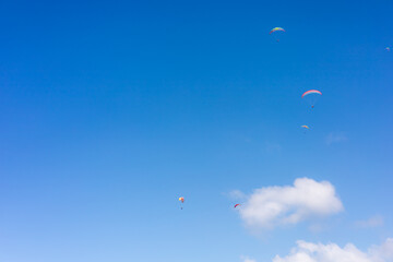 Paragliders soaring under a clear blue sky during a sunny afternoon
