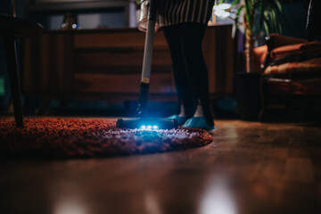 A cozy living room scene featuring a person using a stylish, illuminated vacuum cleaner to clean a carpet, emphasizing cleanliness and modern lifestyle.