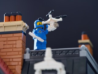 Obraz premium Tambov, Russian Federation - July 09, 2025 Lego blue astronaut minifigure with a drone on a house rooftop.