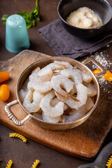  Raw shrimps in a pan and ingredients for making shrimp pasta on the dark background vertical photo