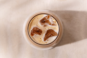 Chilled autumn latte with creamy foam and ice cubes creates a refreshing mood, evoking the comfort...