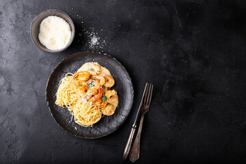 Pasta with shrimps in creamy sauce in a black plate top view copy space for text