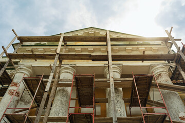 Ancient building with majestic columns surrounded by scaffolding under sunlight symbolizes restoration, hope and architectural revival.