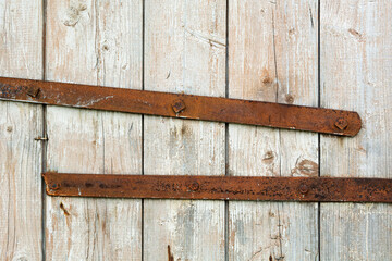 Old rusty metal bars cross weathered wooden planks, creating a striking industrial vintage background with rich texture and nostalgic atmosphere.