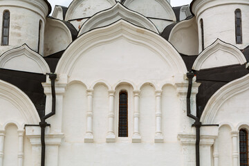 White stone church facade with narrow arched windows, decorative columns, and layered curved shapes creates serene historical atmosphere.