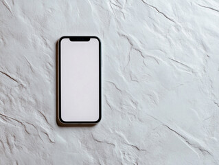 A silver smartphone with a blank white screen lies on a textured surface under soft lighting.