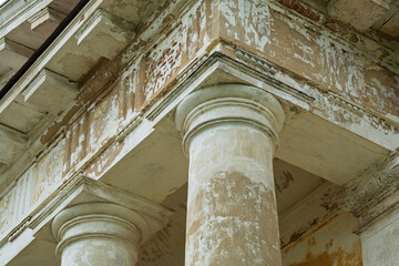 Close-up of weathered neoclassical column and peeling entablature highlights the textured beauty and decay of historic architecture.