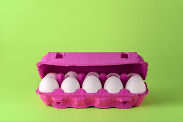 Bright white eggs arranged in a vivid magenta carton on a fresh green background create a playful contrast and cheerful mood.
