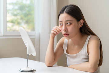 Bored, insomnia asian young woman, girl looking at mirror hand touching under eyes with problem of...